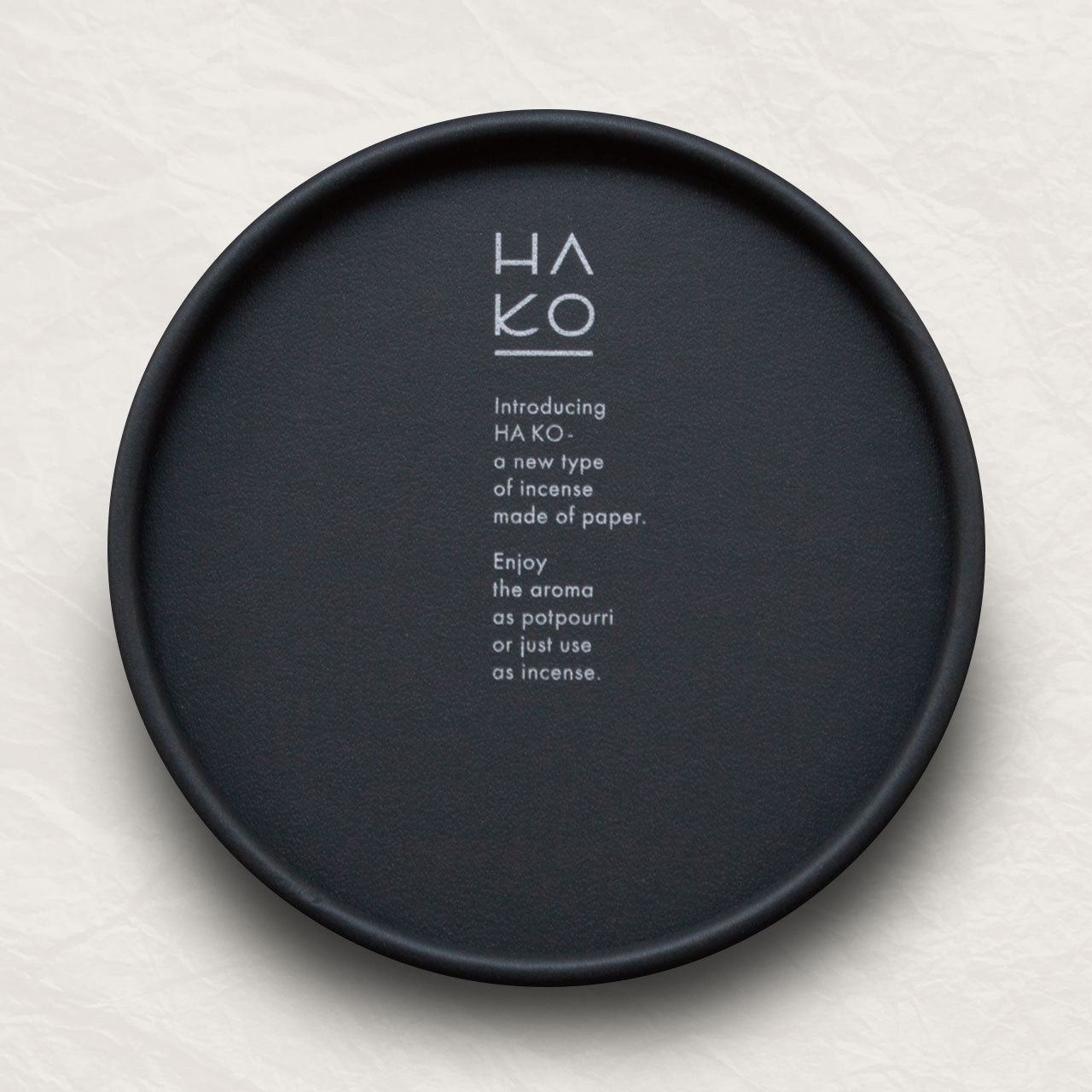 Black circular container with white lettering describing the incense inside