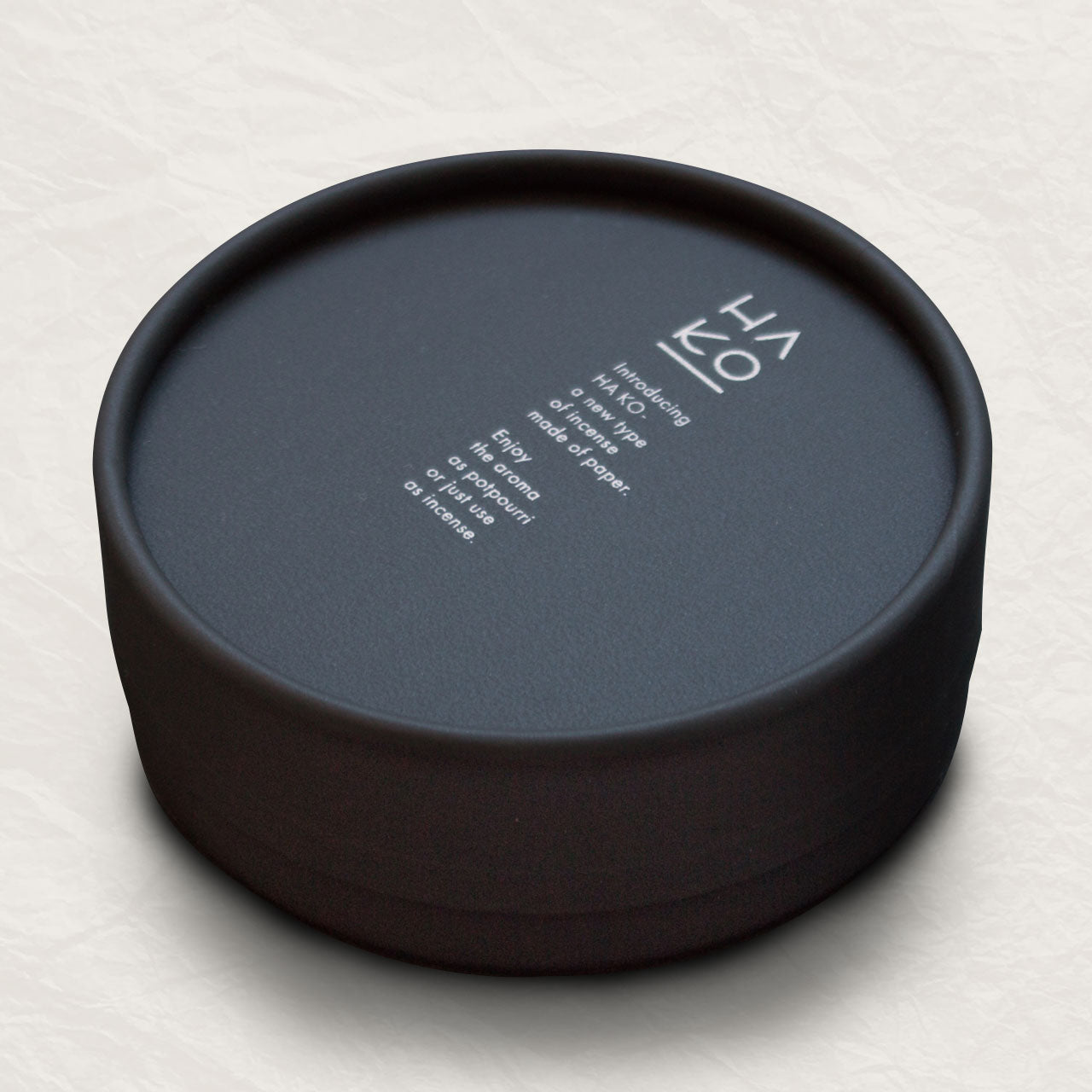 Black circular container with white lettering describing the incense inside