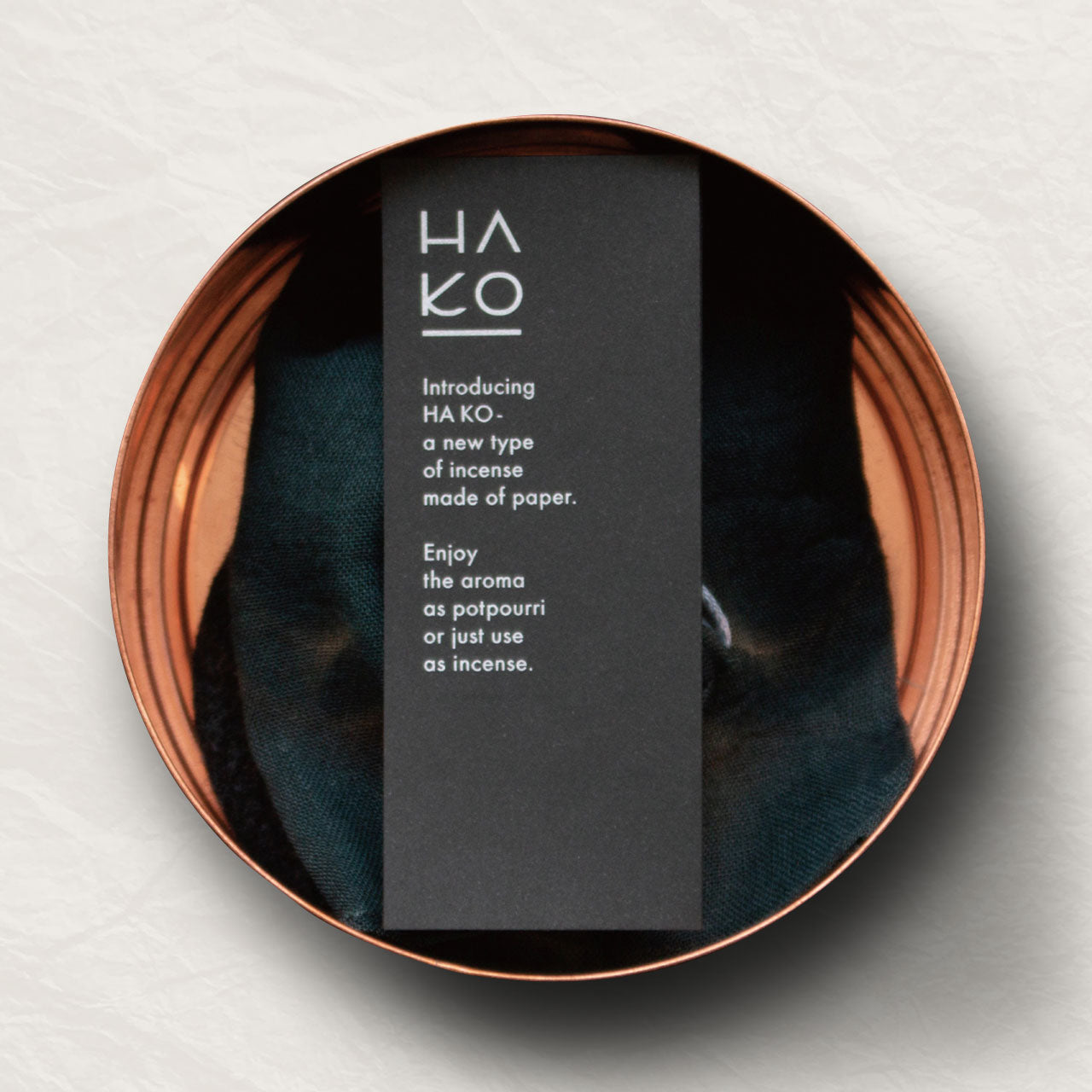 A copper container with a black card describing the incense inside