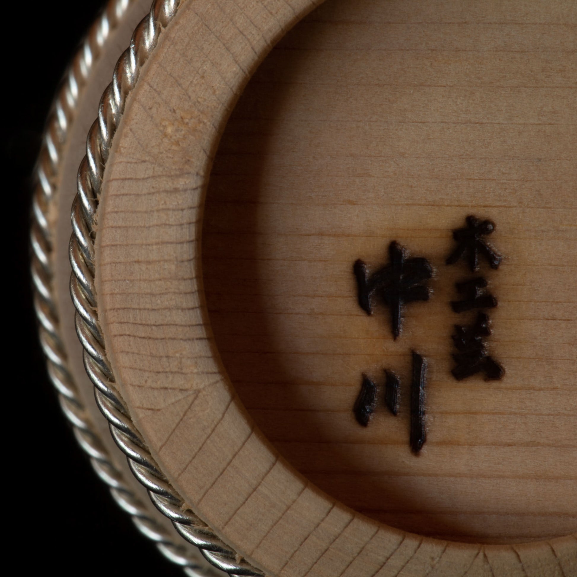 Detail of bottom of wooden Hinoki sake cup with branded lettering
