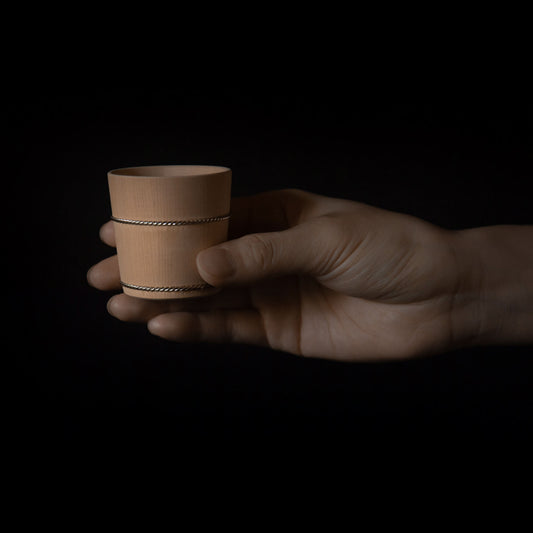Hand holding a wooden Hinoki sake cup